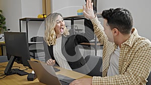 Man and woman business workers working high five at office