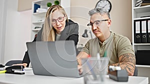 Man and woman business workers working together using laptop at the office