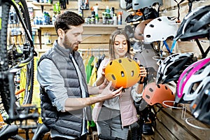 Man and woman buying helmet in the bicycle shop