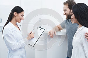 A man and a woman came to see a dentist. The receptionist fills in the form and interviews the patients.