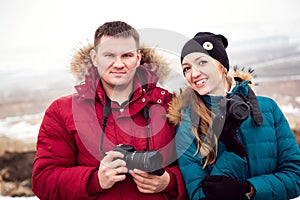 A man and a woman with cameras travel in winter