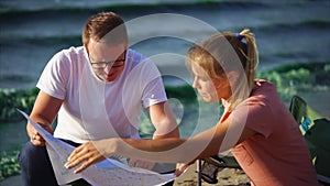 Man and woman are in camp by the river and exploring country map