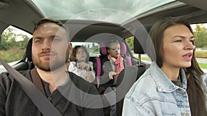 Man and woman with children driving in car, two parents and children traveling and dancing in tre transport. Happy