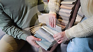 A man and woman choosing upholstery fabric color and texture from various colorful samples for sofa in a store, close up