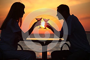 Man and woman clink glasses on sunset outside photo