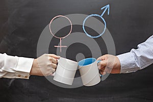 A man and a woman clink mugs against a background of gender symbols. Concept of gender equality