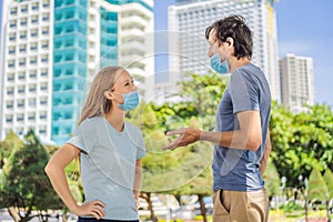 A man and a woman are communicating on the street with incorrectly worn face masks. Improper wearing of medical masks