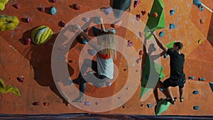 A man and a woman compete in a gym on a climbing wall