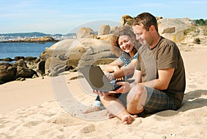 Man and woman with computer at beach