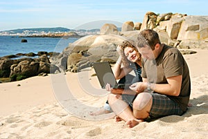 Man and woman with computer at beach