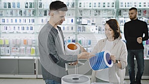 A man and a woman in a consumer electronics store choose a portable air purification system and a quality HEPA filter