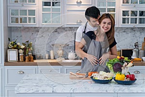 Man and woman cooking organic vegetable salad healthy food in kitchen lifestyle meal preparation at home. Happy young