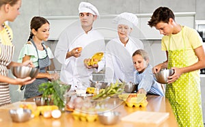 Man and woman cooks, during culinary master class, tell children rules when preparing dough