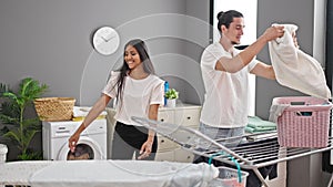 Man and woman couple doing laundry dancing at laundry room