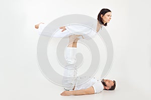 Man and woman, couple doing sports exercises, fitness and yoga. Male holding female on legs, practicing postures, trust