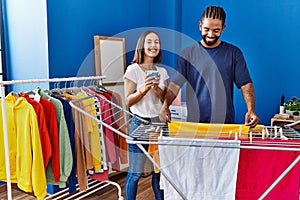 Man and woman couple drinking coffee hanging clothes on clothesline at laundry