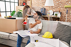 Man and woman couple drinking coffee looking house plans at new home