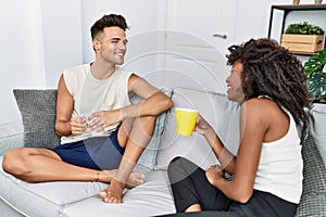 Man and woman couple drinking coffee sitting on the sofa at home