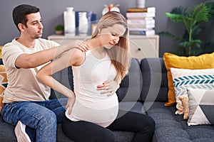 Man and woman couple expecting baby massaging back at home