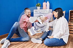 Man and woman couple fighting with clothes at laundry room