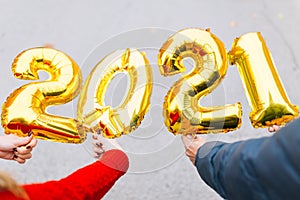 Man and woman couple hands holding gold foil balloons numeral 2021. New year celebration concept