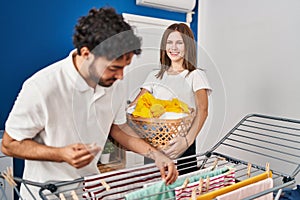 Man and woman couple hanging clothes on clothesline at laundry room