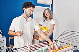 Man and woman couple hanging clothes on clothesline at laundry room