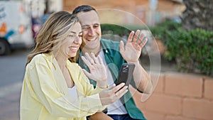 Man and woman couple having video call sitting on bench at park