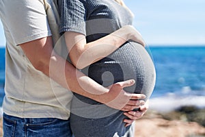 Man and woman couple hugging each other expecting baby at seaside