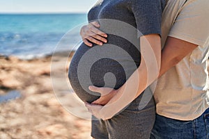 Man and woman couple hugging each other expecting baby at seaside