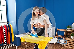 Man and woman couple hugging each other ironing at laundry room
