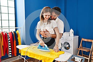 Man and woman couple hugging each other ironing at laundry room