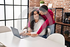 Man and woman couple hugging each other using laptop at home