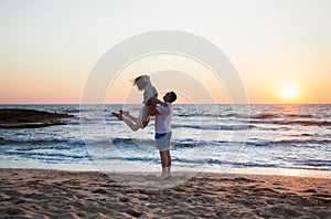 man and woman, couple in love, in full growth are actively having fun on beach against backdrop of sea and sunset