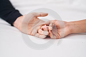 Man and woman couple lying on bed with hands together at bedroom