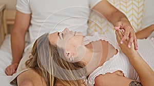 Man and woman couple lying on bed together kissing hand at bedroom