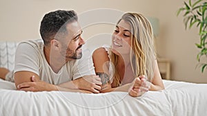 Man and woman couple lying on bed together speaking at bedroom