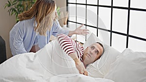 Man and woman couple lying on bed waking up at bedroom