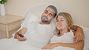 Man and woman couple lying on bed watching tv at bedroom