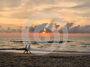 Man and woman couple running joking on the beach on sunset twilight sky silhouette