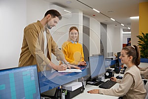 Man and woman couple signing document at modern clinic reception desk