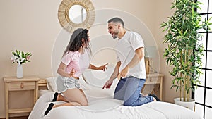 Man and woman couple sitting on bed dancing at bedroom