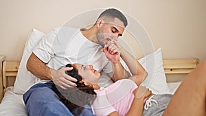 Man and woman couple sitting on bed kissing hand at bedroom