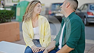Man and woman couple sitting on bench speaking at park