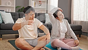 Man and woman couple sitting on floor stretching head at home