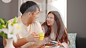 Man and woman couple sitting on sofa drinking coffee at home