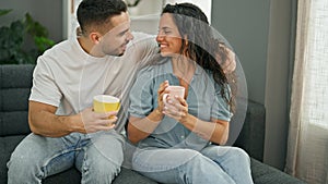 Man and woman couple sitting on sofa drinking coffee at home