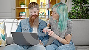 Man and woman couple sitting on sofa shopping with laptop and credit card at home