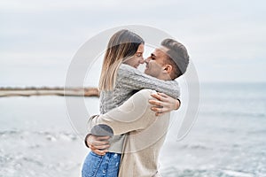 Man and woman couple smiling confident hugging each other at seaside