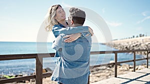 Man and woman couple smiling confident hugging each other turning at seaside